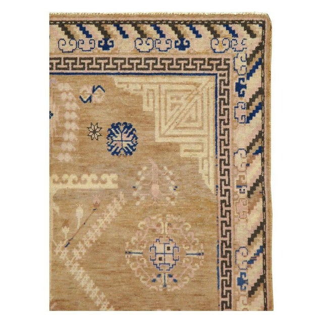 An antique East Turkestan Khotan gallery rug handmade during the early 20th century with a predominately light brown...