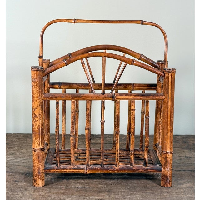 Vintage burnt bamboo magazine rack with an arched carry handle, vertical spindle sides, and open slatted base, showing...