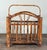 Vintage burnt bamboo magazine rack with an arched carry handle, vertical spindle sides, and open slatted base, showing...