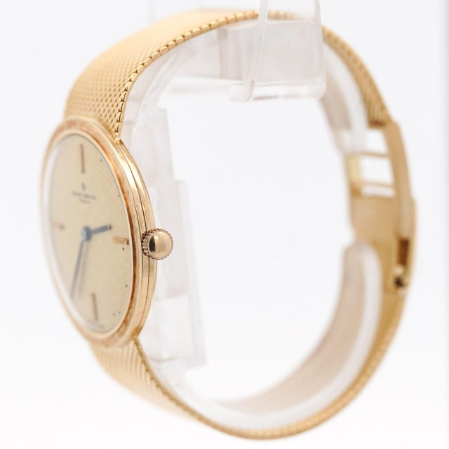 Vintage Baume and Mercier manual-wind wristwatch in 18K yellow gold featuring a 32mm round case with textured champagne...