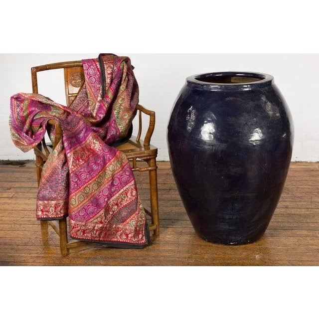 An oversized vintage Thai water vessel from the mid-20th century, with midnight blue glaze, and tapering lines. Created in...