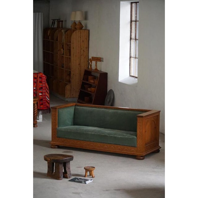 A finely crafted early 20th century freestanding sofa in solid oak, featuring rich hand-carved details and a structured...