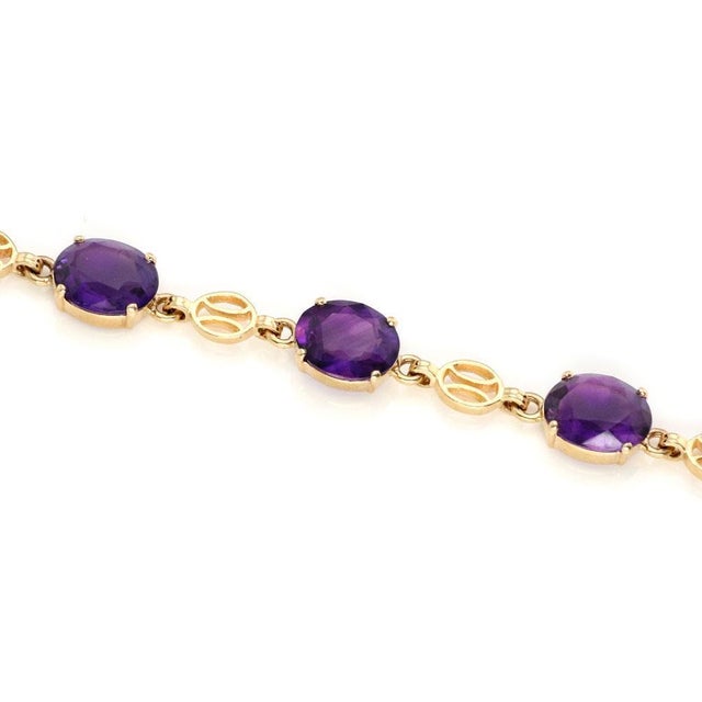 This lovely vintage bracelet is crafted from 14k yellow gold. It has 7 large oval cut amethyst gemstones in oval frames...