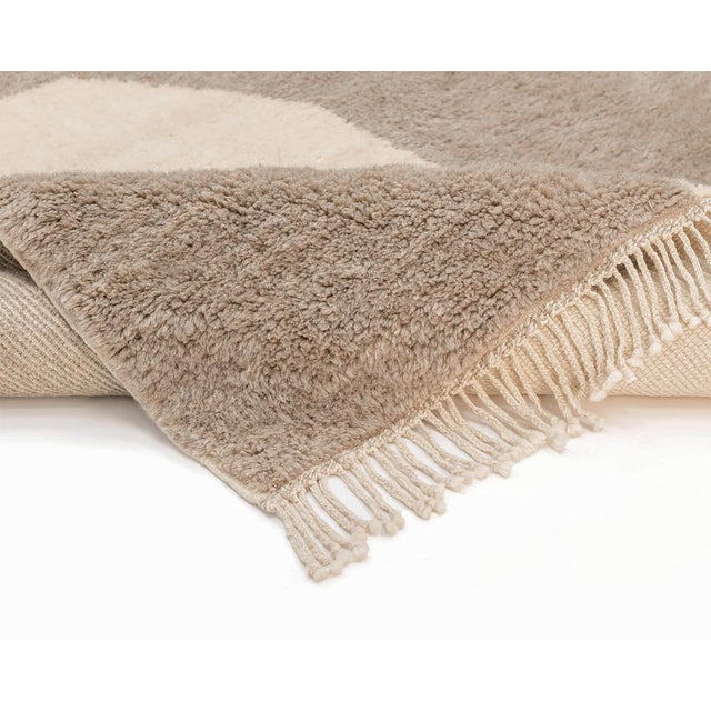 Sophisticated, Hand-knotted wool rug in muted Taupe with contrasting Ivory geometric accents, creating a minimalist yet...