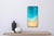 This artwork depicts a serene coastal scene, capturing the gentle transition of turquoise waters meeting a soft, sandy...
