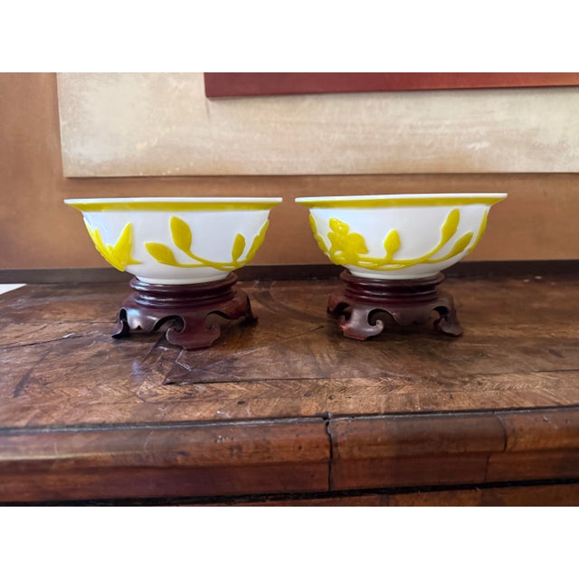 A striking set of two mid-century Peking glass bowls featuring vibrant yellow floral and foliate decoration in relief...