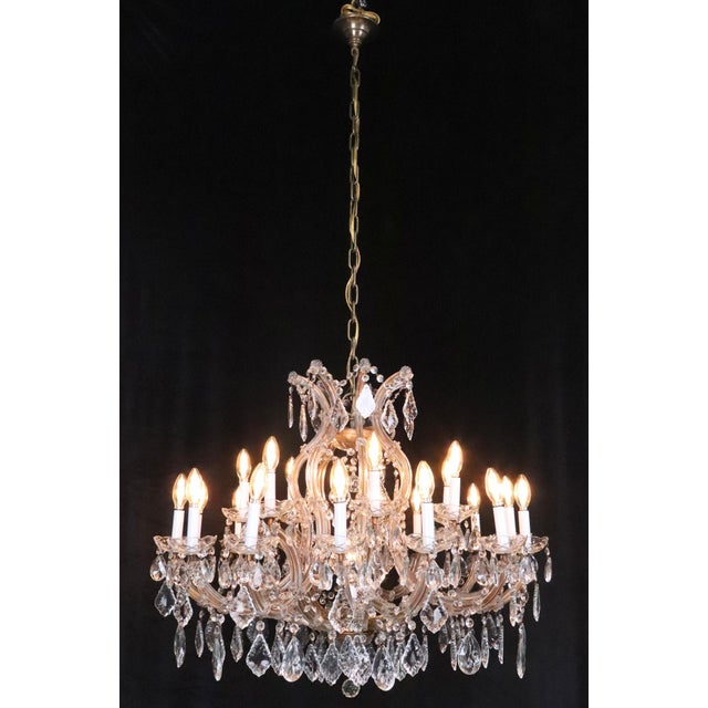 Marie Therese style chandelier with teardrop and pendeloque shaped crystals and a brass frame, canopy, and chain. This...