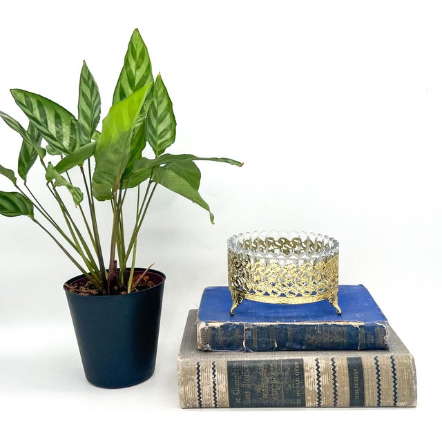 Elegant, mid-late 20th century dish featuring a clear ribbed glass bowl nestled in an ornate gold-tone metal holder....