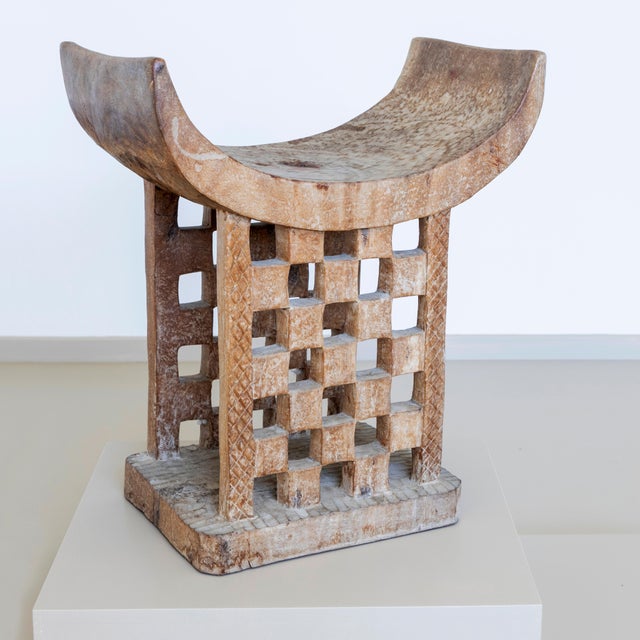 Modern African stool in traditional style. The stool is carved from wood and whitewashed. The stool has a bowl-shaped seat...