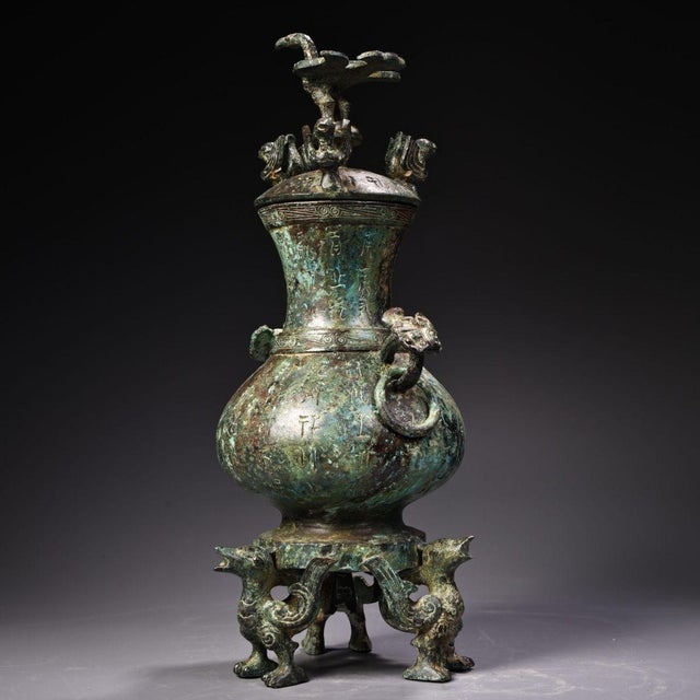 A striking Chinese bronze vase featuring an archaistic design with a rich verdigris (green) patina. The vessel has a...