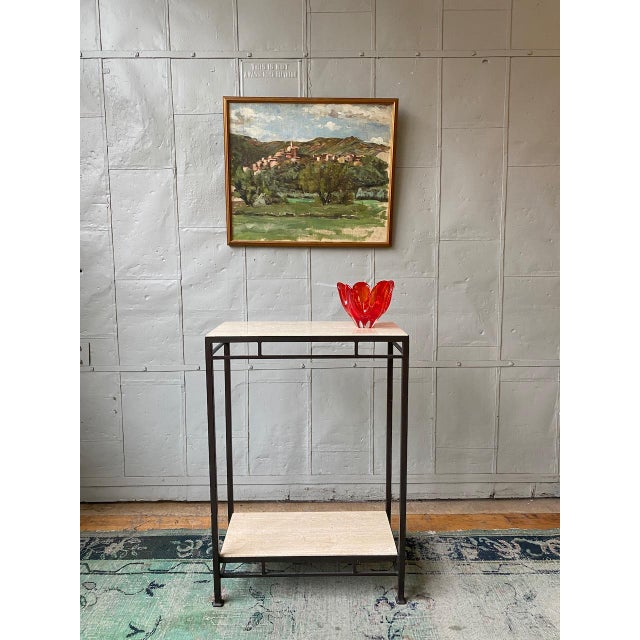 Elegant custom console table featuring a hand-applied bronze-finished iron frame with upper and lower travertine shelves....