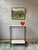 Elegant custom console table featuring a hand-applied bronze-finished iron frame with upper and lower travertine shelves....