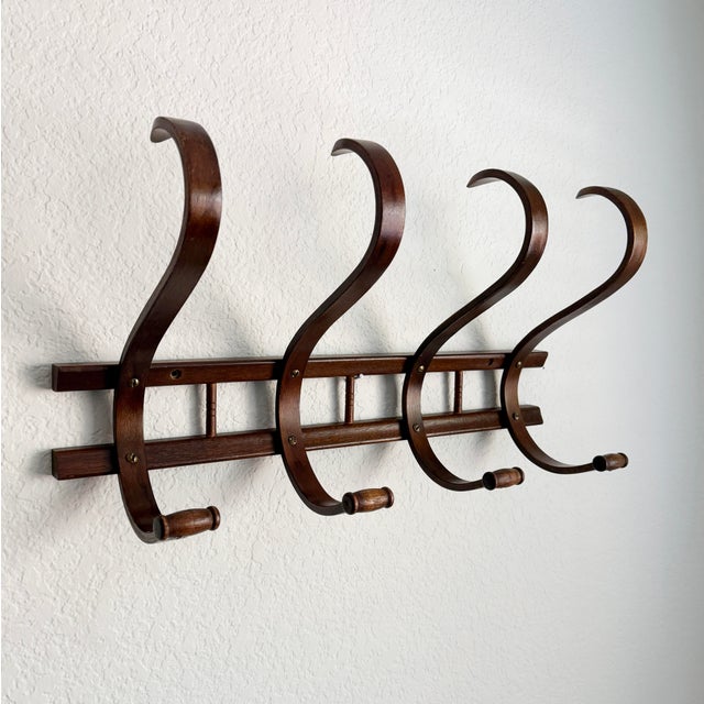 Vintage mid-20th-century bentwood wall-mounted coat rack in the style of Thonet. Made of solid wood, stained in medium to...
