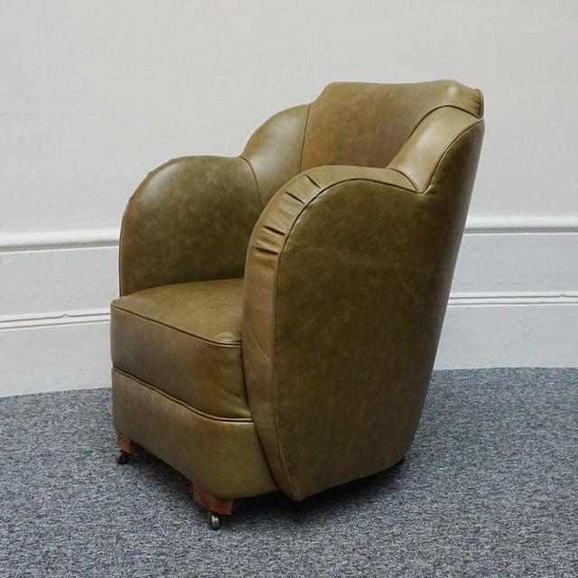 An Art Deco Cloud chair by Harry & Lou Epstein. Original walnut castors, re-upholstered in olive green leather with ruched...