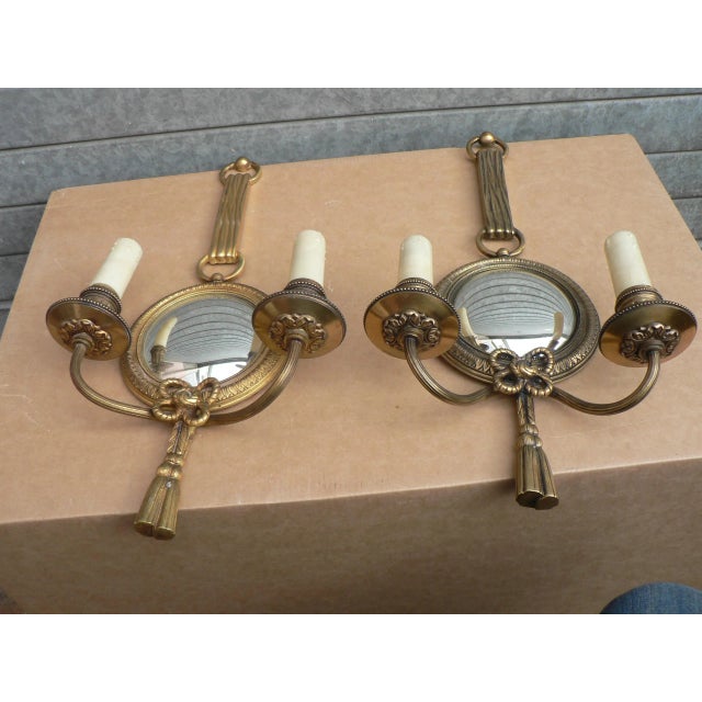 This pair of gilded bronze sconces from the 1950s features convex mirrors and is numbered. This piece has an attribution...