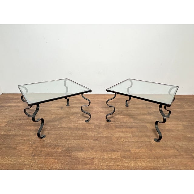 A pair of mid century "ondulation" wrought iron and glass side tables in the manner of French designer Jean Royere.