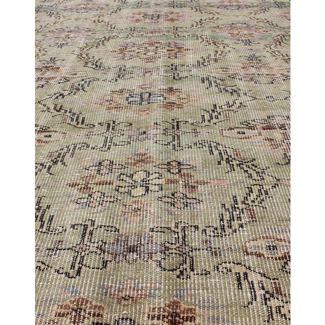 Distressed Turkish Rug with Mid-Century Modern Design. Rendered on a muted background with a floral pattern and speckled...
