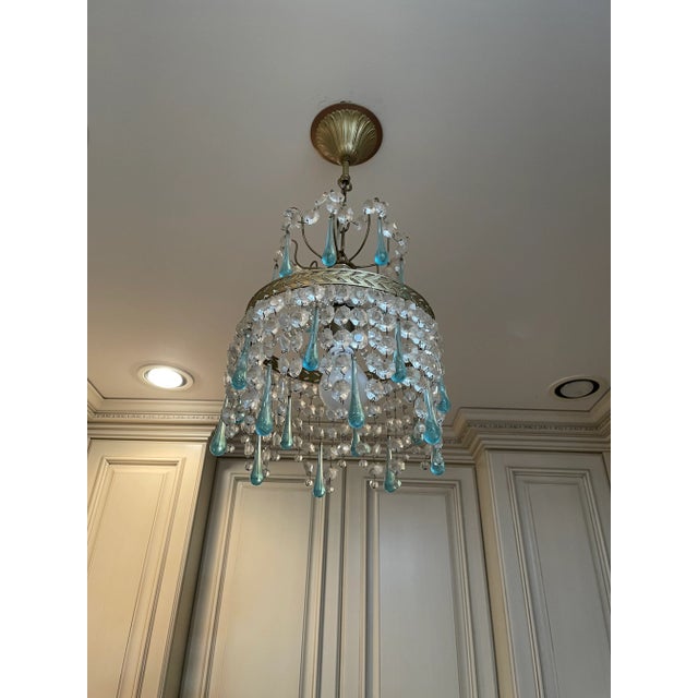 This French pendant chandelier has a soft gold frame. It has the original blue raindrops and crystals hanging on 2 tiers...