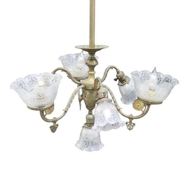 This antique brass chandelier, dating to approximately 1890, features a distinctive design for both electric and gas...