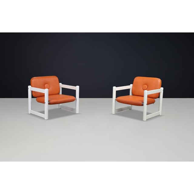 Stylish pair of low lounge chairs from italy, 1970s, featuring white lacquered wooden frames and original cognac skai...