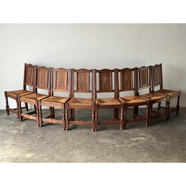Eight antique chairs, one carved motif repeated down the line — a scrolling acanthus panel centered in each chair back,...