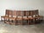 Eight antique chairs, one carved motif repeated down the line — a scrolling acanthus panel centered in each chair back,...