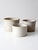 Set of three vintage stoneware crocks in graduated sizes, each with creamy white glaze, softly aged rims, and subtle...