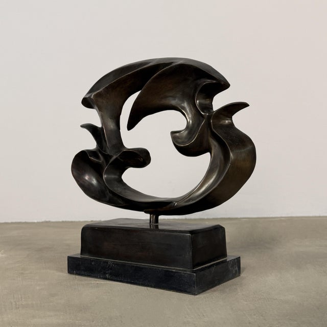 Abstract bronze sculpture featuring fluid, interwoven forms that evoke the motion of birds or doves (or seagulls) in...