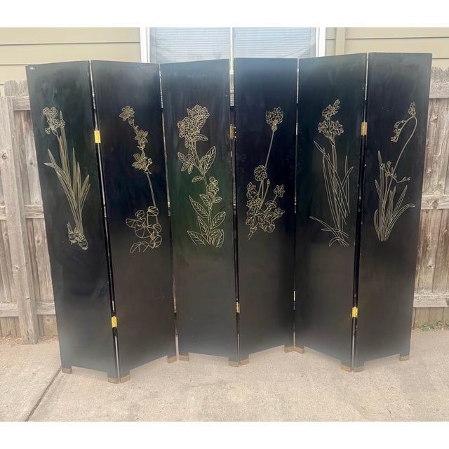 A vintage 20th Century Chinese black-lacquer six-panel folding screen, hand-painted with a traditional garden courtyard...