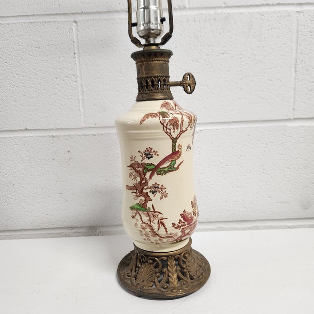 Elegant mid-20th century Chinoiserie porcelain table lamp featuring a detailed pheasant and botanical branch motif on a...