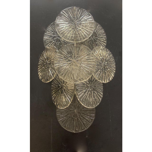 A pair of wall sconces attributed to the Mazzega company. This lamp is composed of numerous clear glass discs, each hand-...