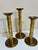 A striking vintage set of three graduated solid brass candlesticks featuring elegant spiral-wrapped columns and...