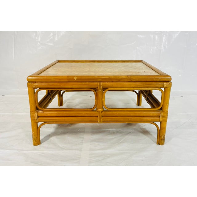 A charming vintage bamboo coffee table featuring a hand-crafted capiz shell inlaid top, dating from the 1970s. This square...