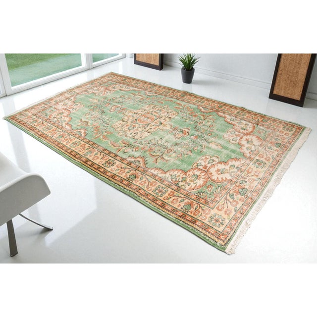 This is a vintage Turkish Oushak rug from the Mid 20th Century. The piece was hand-knotted.