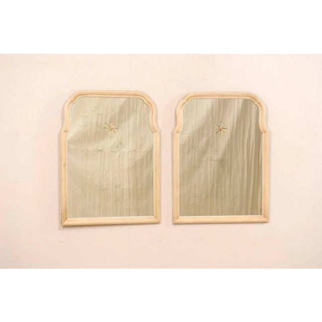 A pair of American mirrors with sunburst églomisé center. These vintage mirrors features a light, neutral toned wooden...