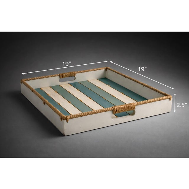 A charming coastal-style wooden serving tray featuring rope-wrapped handles and a slatted base in soft sea-green and...