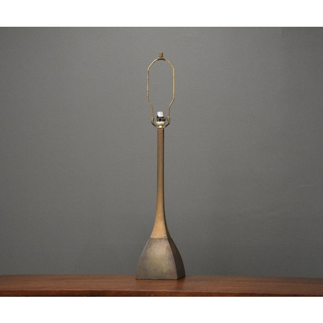 A mid century modern brutalist style bronze table lamp. 6” wide. 6” deep. 32” tall.