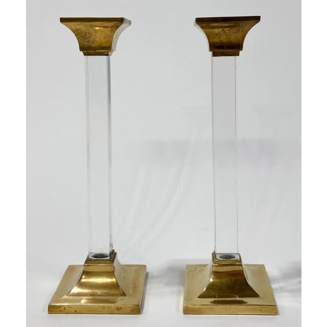 Pair of stately squared lucite and brass candle holders. The pillars have a stunning sharp squared edge that reflects...