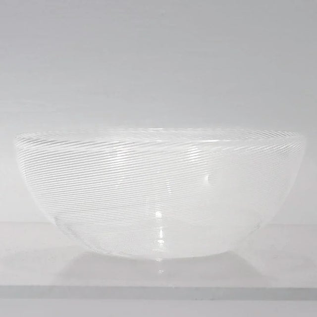 A fine Murano glass bowl. By Venini. In colorless glass with fused thread of opaque white lattimo. Likely inspired by one...