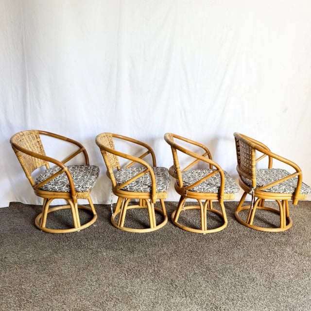 A beautiful set of four boho chic rattan wicker swivel dining chairs featuring curved barrel backs, open-weave cane...