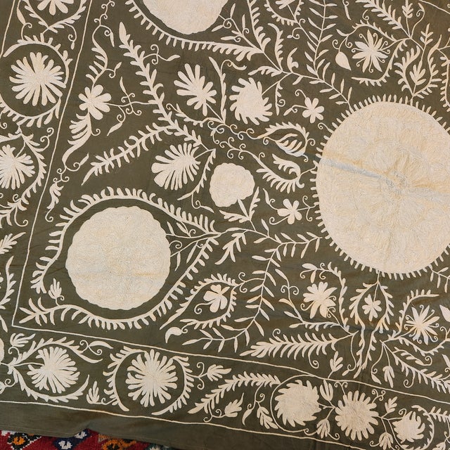 A stunningly beautiful Suzani. Embroidered in cream on an olive green background. Cotton with silk embroidery. Hand...