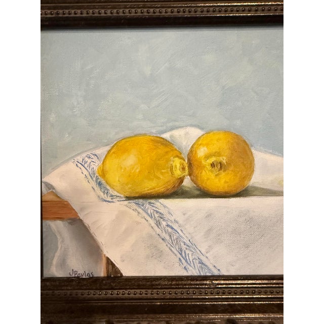 Oil painting by Texas artist, Jill Pavlas, of lemons on a tablecloth. Framed in a custom frame.