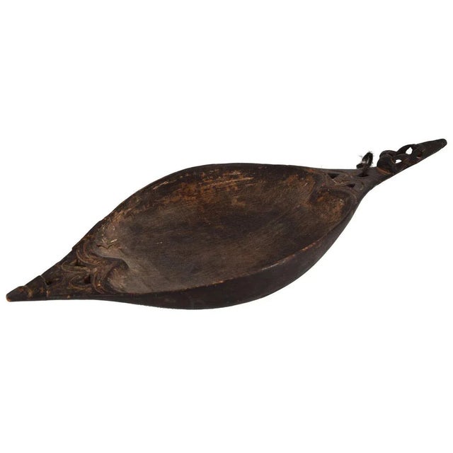 Its elongated oval shape recalls that of a canoe, it has two carved handles shaped like stylized animals. This artwork is...
