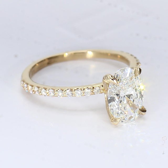 This is an 18k Yellow Gold Engagement Ring with a Central Oval Diamond, accented by Round Diamonds. Center Stone - 1x Oval...