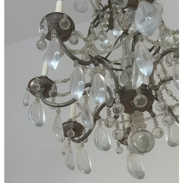 This elegant chandelier features ornate metal arms adorned with cascading glass teardrop crystals, creating a timeless and...