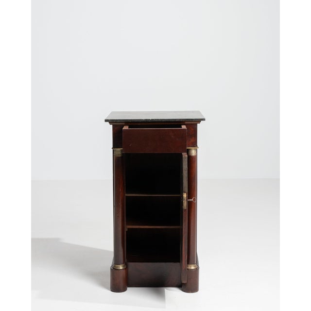 Mahogany pedestal cabinet in Rich Mahogany. Its rich mahogany finish sets off black marble top, brass mounts, plinth base,...