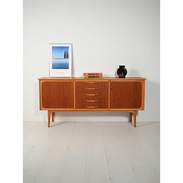 Scandinavian teak and oak sideboard from the 1950s/1960s, featuring two compartments with shelves and central drawers with...