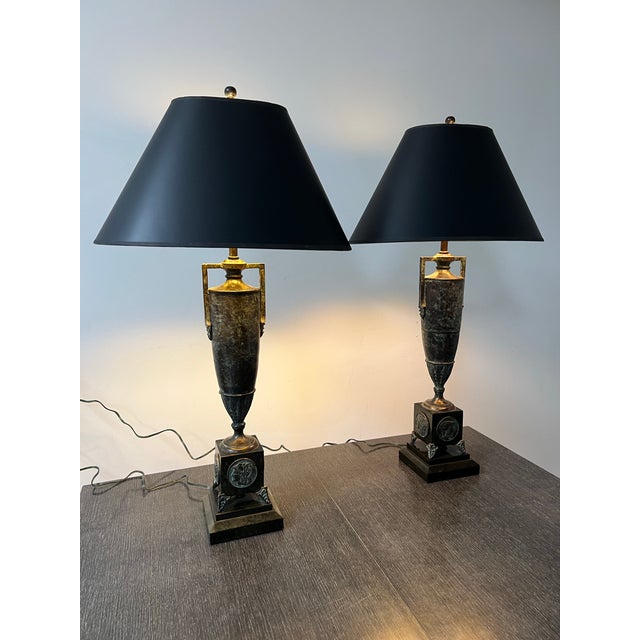 These timeless Lamps comprise a verdigris patinated bronze handled urn that sit on a marble wax-stone base decorated with...