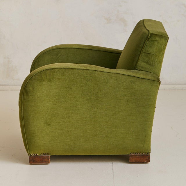 A 1950s Italian lounge chair defined by its Art Deco silhouette. The form is sculpted with dramatic curvesrounded arms...