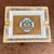 A rectangular porcelain catchall or cigar ashtray by Hermès Paris featuring a central French emblem design with gold trim